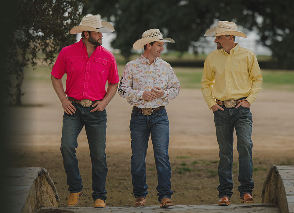 Three guys wearing western apparel walking